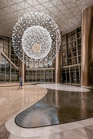 A large room with a chandelier and a person walking.